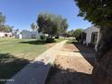 Manicured lawns and mature trees frame sidewalk path, offering shaded walkways and tranquil common area at 4652 W Desert Crest Dr, Glendale, AZ 85301