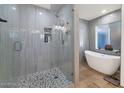 Modern bathroom with a glass-enclosed shower, stone floor, a soaking tub and natural light from a window at 524 W Sunset Cir, Mesa, AZ 85201