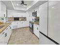 Modern kitchen featuring white cabinets, granite countertops, tile flooring, and stainless steel appliances at 524 W Sunset Cir, Mesa, AZ 85201