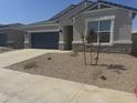 Inviting single-story house boasts a two-car garage, gray exterior, stone details and well-kept landscaping at 17738 W Onyx Ave, Waddell, AZ 85355