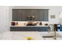 The spacious kitchen features stone countertops, gray cabinetry, a decorative backsplash, and stainless steel appliances at 21134 W Minnezona Ave, Buckeye, AZ 85396