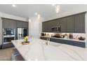 Bright modern kitchen features a center island, stainless appliances, gray cabinetry and stone countertops at 21134 W Minnezona Ave, Buckeye, AZ 85396