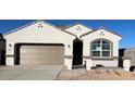 Charming single-Gathering home with a two-car garage, tan paint, a gated porch, and desert landscaping at 25478 W Graham Trl, Buckeye, AZ 85326