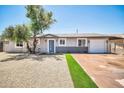 The house features a blue door and white garage, complemented by a landscaped front yard with gravel and artificial turf at 5236 S 19Th Ave, Phoenix, AZ 85041