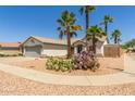 Single-story home with desert landscaping, mature palm trees, and a gray two-car garage at 7924 W Hammond Ln, Phoenix, AZ 85043