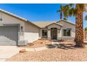 Inviting single-story home featuring desert landscaping, mature palm trees, and a gray two-car garage at 7924 W Hammond Ln, Phoenix, AZ 85043