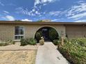 Close-up of the arched entryway, brick facade, and manicured landscaping around the front of the property at 1118 E Orangewood Ave, Phoenix, AZ 85020