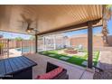 This backyard has a covered patio seating area, a fire pit, a pool with a pergola and privacy fencing at 11252 E Edgewood Ave, Mesa, AZ 85208