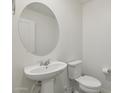 Compact half bath with a pedestal sink, round mirror, and a white toilet for guest convenience at 12531 W Glenn Dr, Glendale, AZ 85307