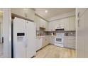 Well-lit kitchen featuring modern white appliances, light wood flooring, and coordinated backsplash tiles at 16537 N Oachs Dr, Surprise, AZ 85374