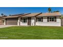 Charming single-story home with a well-manicured lawn and a two-car garage, complemented by solar panels at 1906 N Evergreen St, Chandler, AZ 85225