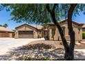 Attractive desert home featuring a three-car garage, neutral stucco, tile roof, and desert landscaping at 21284 E Camacho Rd, Queen Creek, AZ 85142