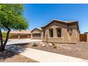View of front of house showing stucco, desert landscaping, and three-car garage at 21284 E Camacho Rd, Queen Creek, AZ 85142