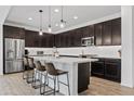 Modern kitchen boasts stainless steel appliances, dark cabinetry, a central island, and stylish pendant lighting at 22938 E Calle Luna --, Queen Creek, AZ 85142