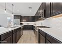 Contemporary kitchen featuring stainless steel appliances, dark cabinets, subway tile backsplash, and hardwood floors at 22938 E Calle Luna --, Queen Creek, AZ 85142