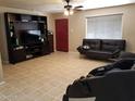 Spacious living room with tile floors, a ceiling fan, black couches, and a large media center at 6011 N 33Rd Ave, Phoenix, AZ 85017