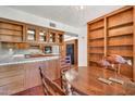 Warm kitchen featuring classic wood cabinetry, tile countertops, and views to an adjacent dining area and built-in shelving at 7037 N 11Th Dr, Phoenix, AZ 85021