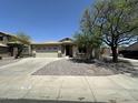 Charming single story home featuring a two-car garage, desert landscaping, and mature trees at 7419 S 45Th Ave, Laveen, AZ 85339