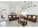 Bright living room featuring vaulted ceilings, a marble accent wall, and two comfortable leather couches at 9814 W Menadota Dr, Peoria, AZ 85382