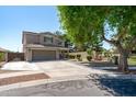 Stunning exterior view of a two-story home with a spacious driveway and lush landscaping, complemented by mature shade trees at 12546 N 142Nd Ln, Surprise, AZ 85379
