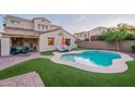 Beautiful backyard featuring a sparkling pool, lounge chairs, well-manicured lawn, and covered patio at 13318 W Indianola Ave, Litchfield Park, AZ 85340