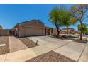 Side view of a single-story home with a two-car garage, tile roof, and a driveway; desert landscaping in front at 16219 W Yucatan Dr, Surprise, AZ 85379