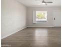 Bright living room with wood-look floors, a ceiling fan, and a large window at 1628 E Sunland Ave, Phoenix, AZ 85040