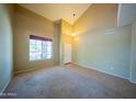 Bright living room featuring a tile and carpet, high ceilings, and a large window at 17433 W Holland Ln, Surprise, AZ 85388