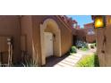 Charming front entrance with an arched entryway, white door, brick pathway, and desert landscaping at 5640 E Bell Rd # 1047, Scottsdale, AZ 85254