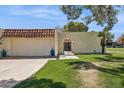 Home exterior featuring an arched gate, stucco wall, a garage, and desert landscaping at 6147 E Lewis Ave, Scottsdale, AZ 85257