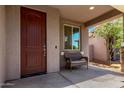 Inviting covered porch with a bench and a dark wood front door offers a welcoming spot to relax and enjoy the outdoors at 932 W Capulin Trl, San Tan Valley, AZ 85140