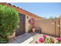 Private courtyard featuring decorative metal door, flowering bushes, and desert decor at 12441 W Windsor Blvd, Litchfield Park, AZ 85340