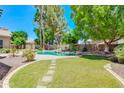 Manicured backyard with lush lawn, stone pathway, desert landscaping, and pool at 1470 W Bartlett Way, Chandler, AZ 85248