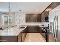 Contemporary kitchen with dark cabinets, stainless steel appliances, and a large island with seating at 15824 W Kendall St, Goodyear, AZ 85338