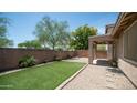 Well-maintained backyard with artificial turf, desert landscaping, and a covered patio at 3439 W Darien Way, Phoenix, AZ 85086