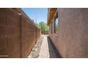 Paver walkway along the side of the house with stucco walls and desert landscaping at 3439 W Darien Way, Phoenix, AZ 85086