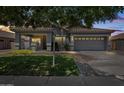 Charming single-Gathering home with lush green lawn and warm exterior lighting at 4140 E Claxton Ave, Gilbert, AZ 85297