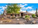 Single-story home with desert landscaping, rocks, and a mature shade tree at 5861 E Anderson Dr, Scottsdale, AZ 85254