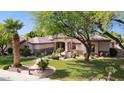 Single-story home with mature trees, green lawn, desert landscaping, and covered front entry at 6428 W Eugie Ave, Glendale, AZ 85304