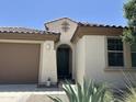 Close up of a home entrance with a dark green front door, desert plants, and an arched portico at 25931 W Deer Valley Rd, Buckeye, AZ 85396
