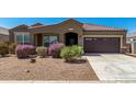 Charming home boasts desert landscaping, including vibrant bushes, and a two-car garage at 38005 W Montserrat St, Maricopa, AZ 85138