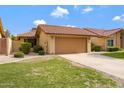 Front view of a single-level home featuring a terra cotta tile roof, a two-car garage, and a green lawn at 4790 E Navajo St, Phoenix, AZ 85044