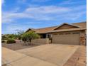 Side view of a single-story home with a brown roof, two-car garage, and well maintained front yard at 6546 E Dallas St, Mesa, AZ 85205