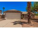 Charming single-story home featuring a well-maintained lawn, mature trees, and a two-car garage at 7426 W Cholla St, Peoria, AZ 85345