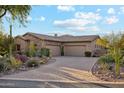 Expansive desert home with brick paved driveway leading to multi-car garage, mature desert landscaping, and stone accents at 7846 E Wilderness Trl, Gold Canyon, AZ 85118