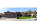 Elegant home exterior with a three-car garage, manicured lawn, and stone accents, nestled in a scenic neighborhood at 136 E Desert Wind Dr, Phoenix, AZ 85048