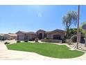 Well-maintained front yard with artificial turf, lush landscaping, and a circular driveway leading to a spacious home at 136 E Desert Wind Dr, Phoenix, AZ 85048