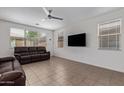 Cozy living room with a ceiling fan, tile flooring, and multiple windows providing natural light at 14180 W Willow Ave, Surprise, AZ 85379