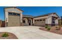 Spacious driveway leading to a two-car garage of a neutral-colored home with stone accents at 17324 W Royal Palm Rd, Waddell, AZ 85355