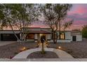 Charming home exterior with desert landscaping, walkway lighting, and attractive architectural features under a twilight sky at 1736 N Ashbrook Cir, Mesa, AZ 85213